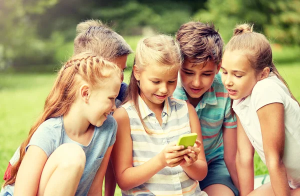 Barn eller vänner med smartphone i sommaren park — Stockfoto