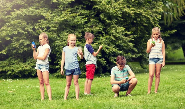 Enfants avec smartphones jouer au jeu dans le parc d'été — Photo