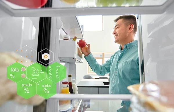 Uomo che prende mela dal frigorifero a casa cucina — Foto Stock