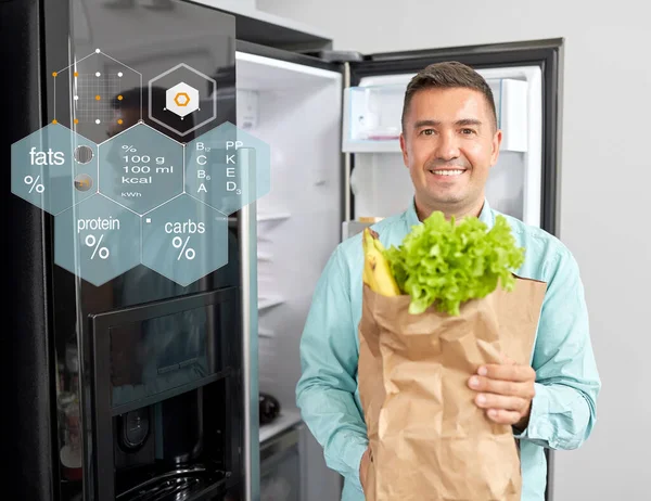 Человек с новой приобретенной едой на домашнем холодильнике — стоковое фото