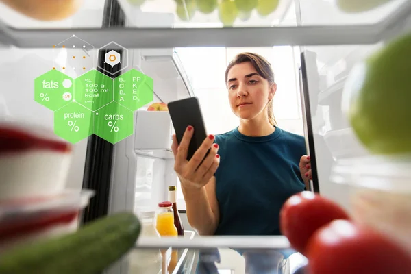 Donna con smartphone e cibo in frigo — Foto Stock