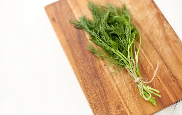 Bunch of dill on wooden cutting board — Stockfoto
