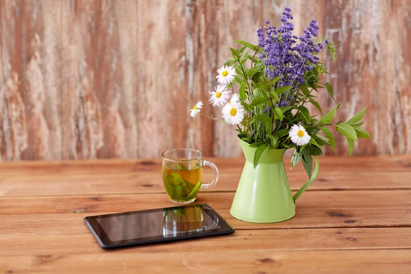 Computador tablet, chá de ervas e flores em jarro — Fotografia de Stock