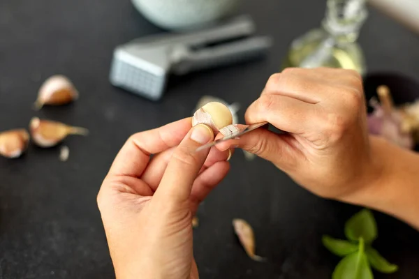 Hands peeling garlic with knife for pesto sauce — Zdjęcie stockowe