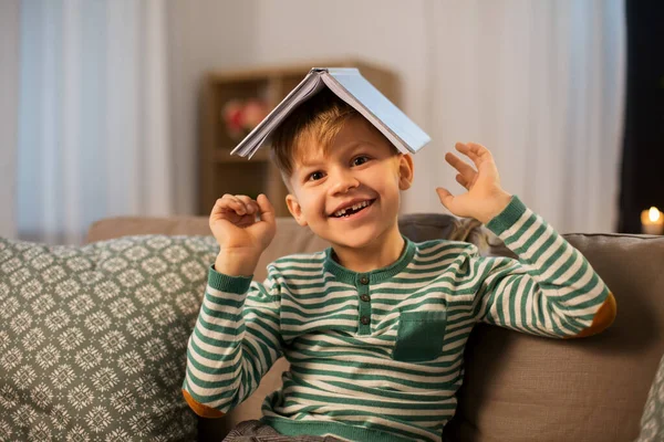 Glad liten pojke med bok ha kul hemma — Stockfoto