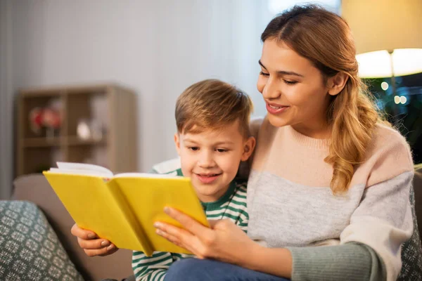 Gelukkig moeder en zoon lezen boek bank thuis — Stockfoto