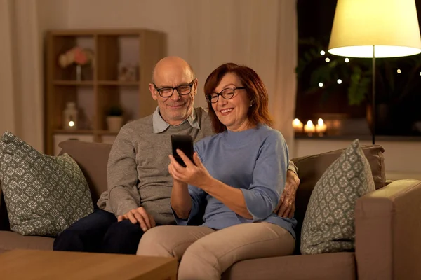 Glückliches Seniorenpaar mit Smartphone zu Hause — Stockfoto