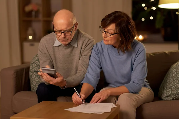 Couple aîné avec papiers et calculatrice à la maison — Photo