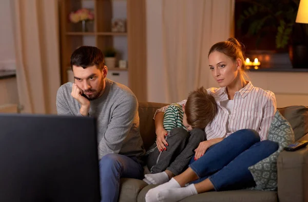 Семья смотрит что-то скучное по телевизору по ночам — стоковое фото