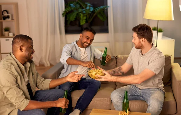 male friends drinking beer with crisps at home