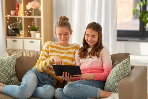 Meninas felizes com tablet pc sentado no sofá em casa — Fotografia de Stock