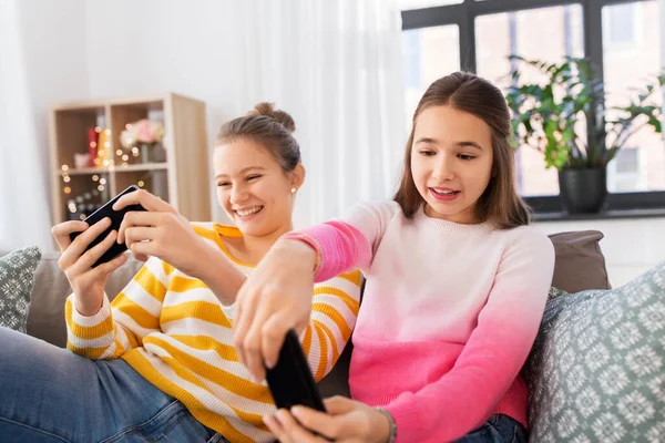 Girls and playing game on smartphones at home — Stock fotografie