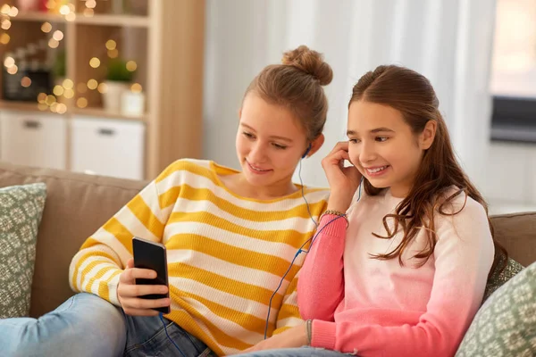 Gelukkig meisjes met smartphone en oortjes thuis — Stockfoto