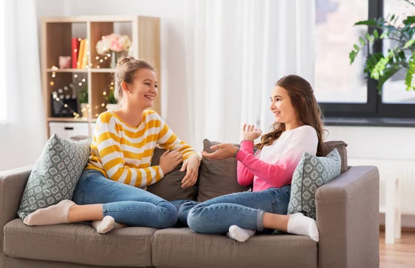 Happy teenage girls talking on sofa at home — Stock Photo, Image