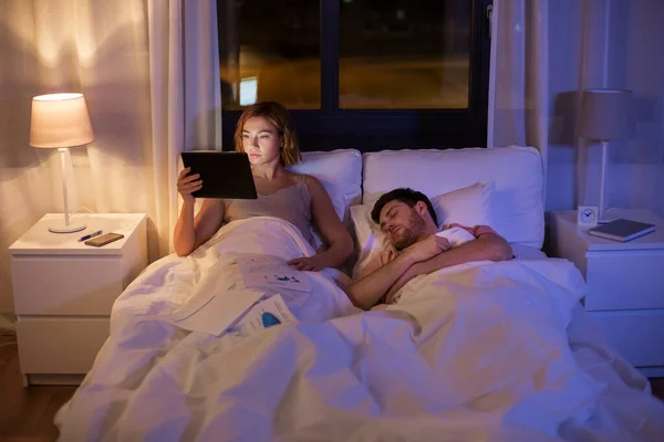 Woman with tablet computer working in bed at night — Stock Photo, Image