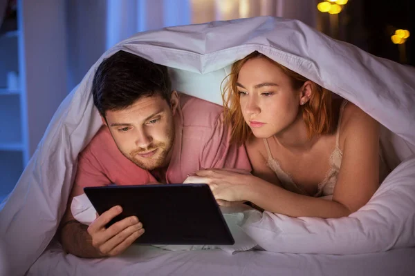 Couple using tablet pc in bed at night — Φωτογραφία Αρχείου