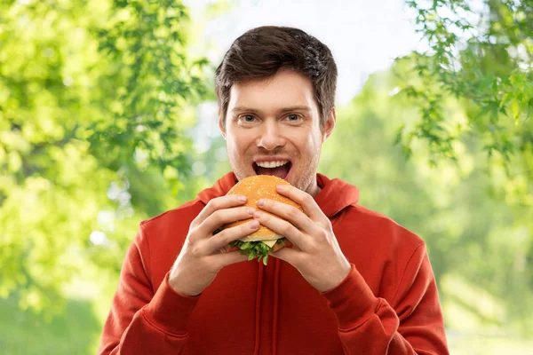 Šťastné mladé muže jíst hamburger — Stock fotografie