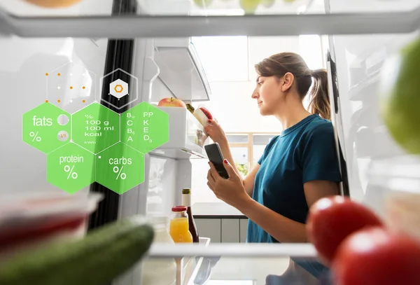 Женщина со смартфоном и едой в холодильнике — стоковое фото