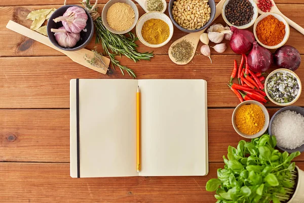 Notebook with pencil among spices on wooden table — Stockfoto