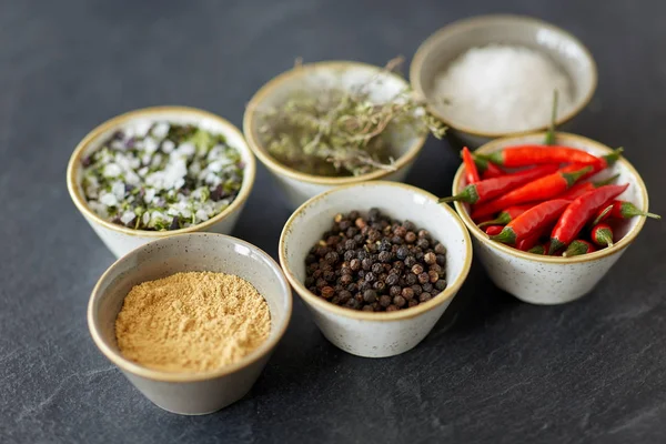 Bowls with different spices on slate stone table — Stockfoto