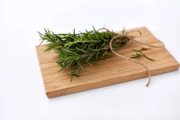 Bunch of rosemary on wooden cutting board — Stock fotografie
