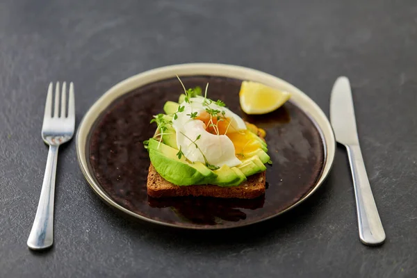 Pane tostato con avocado affettato e uovo imbustato — Foto Stock