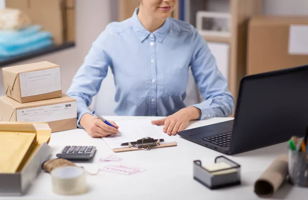 Femme avec ordinateur portable et presse-papiers au bureau de poste — Photo