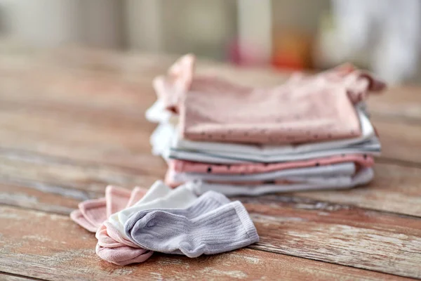 Baby clothes on wooden table at home — Stockfoto