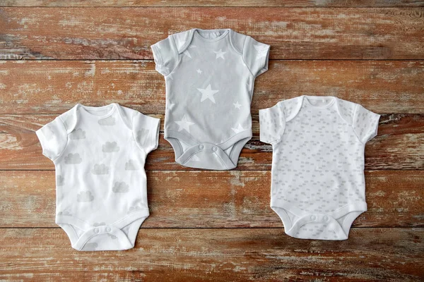 Baby clothes set of bodysuits on wooden table — ストック写真