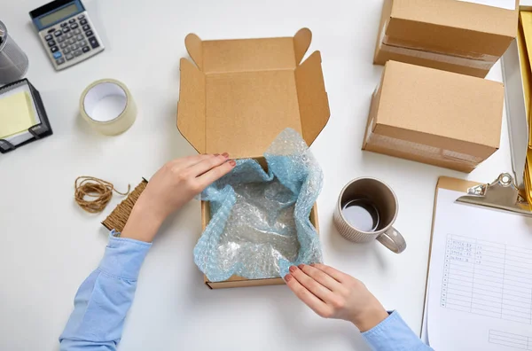 Hands packing mug to parcel box at post office — 스톡 사진