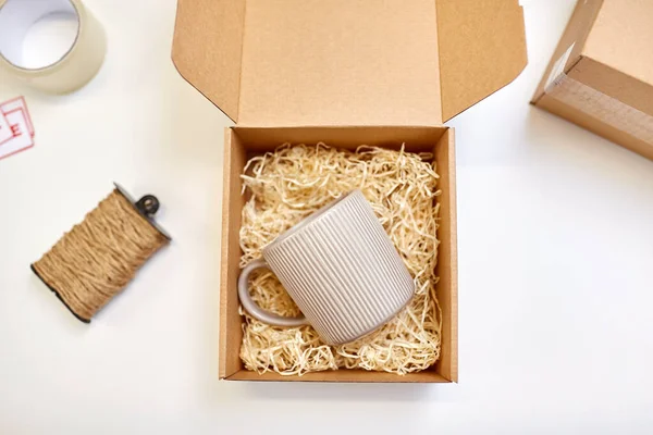 Parcel with straw filler and mug at post office — Stock Photo, Image