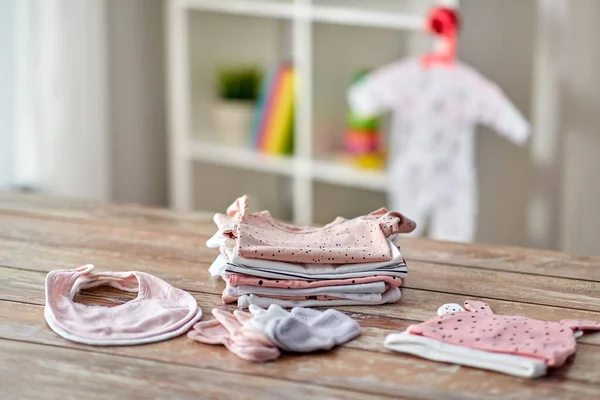 Baby clothes on wooden table at home — Stok fotoğraf