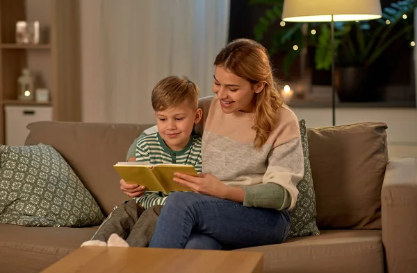 Happy mother and son reading book sofa at home — Stockfoto