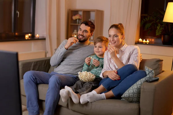 Gelukkige familie met popcorn kijken tv thuis — Stockfoto