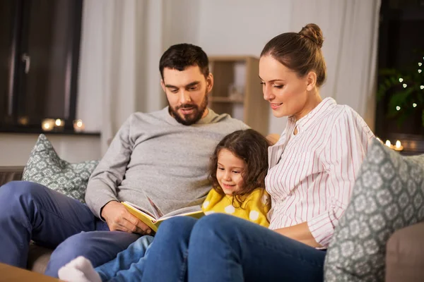 Lycklig familj läsa bok hemma på natten — Stockfoto