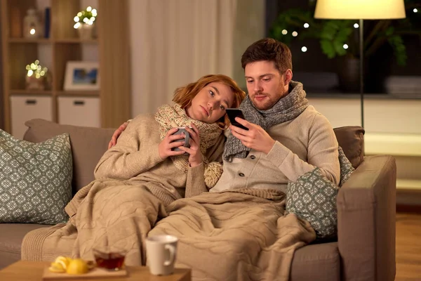 Sick young couple with smartphone at home — Stock fotografie