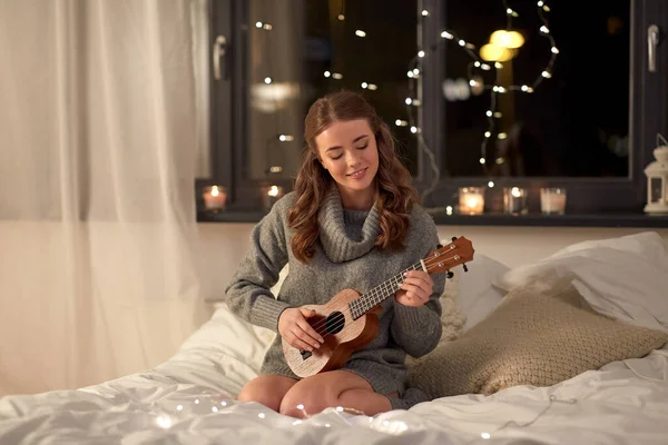 Feliz joven tocando la guitarra en la cama en casa — Foto de Stock