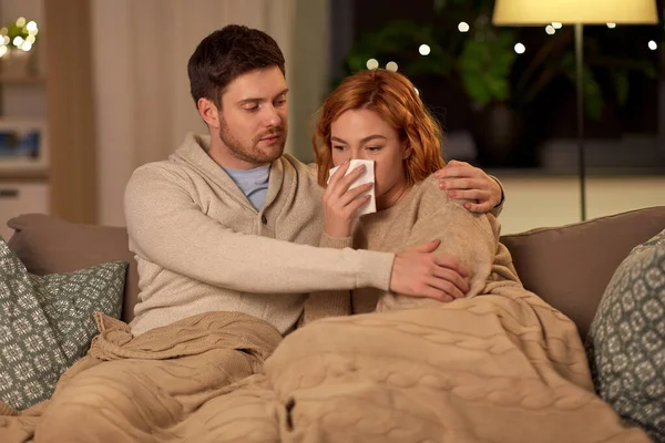 Enferma joven pareja con tejido sonándose la nariz en casa — Foto de Stock