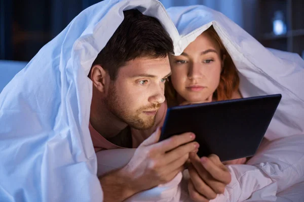 Couple using tablet pc in bed at night — 图库照片