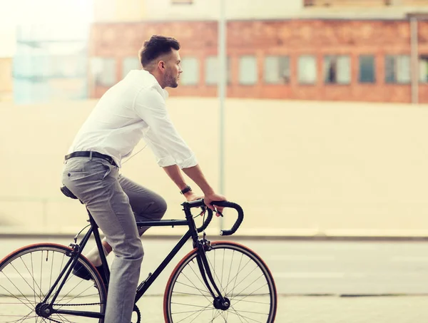 Uomo con cuffie in sella alla bicicletta sulla strada della città — Foto Stock