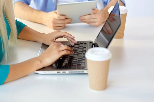 Kobieta wpisując na laptopie i filiżanki kawy na stole — Zdjęcie stockowe