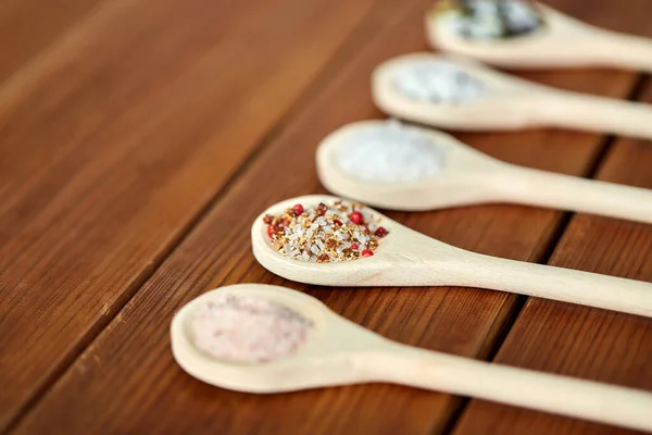 Sendok dengan garam dan rempah-rempah di atas meja kayu — Stok Foto