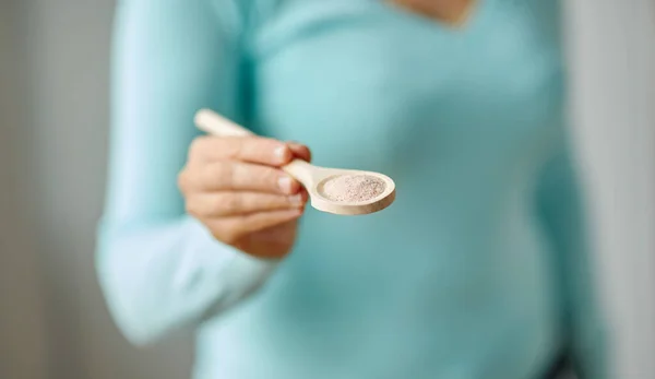 Primer plano de la mujer con sal marina en cuchara de madera —  Fotos de Stock