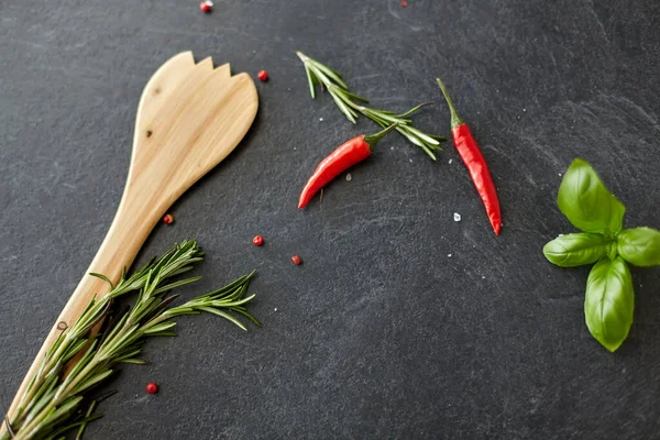 Rosemary, basil and chili pepper on stone surface — Stockfoto