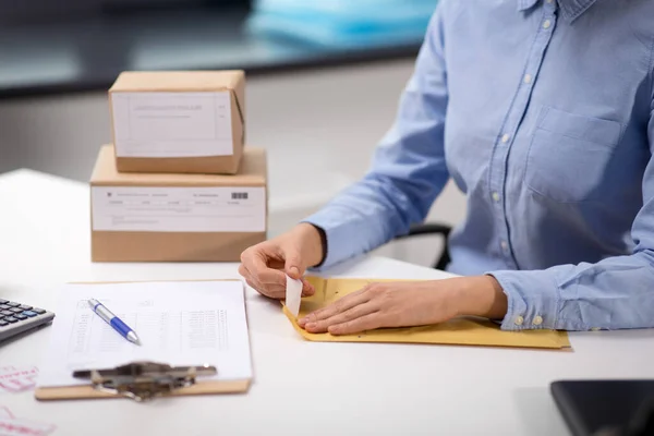 Femme enlever l'autocollant de l'enveloppe avec le colis — Photo