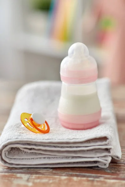 Biberón con leche maternizada, chupete y toalla — Foto de Stock