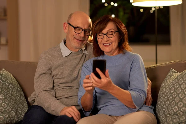 Heureux couple aîné avec smartphone à la maison — Photo