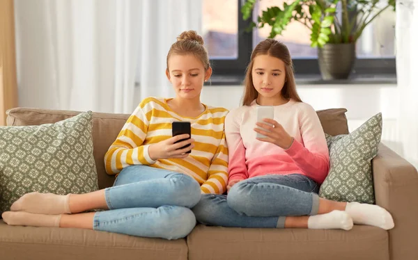 Ragazze con smartphone sedute sul divano di casa — Foto Stock