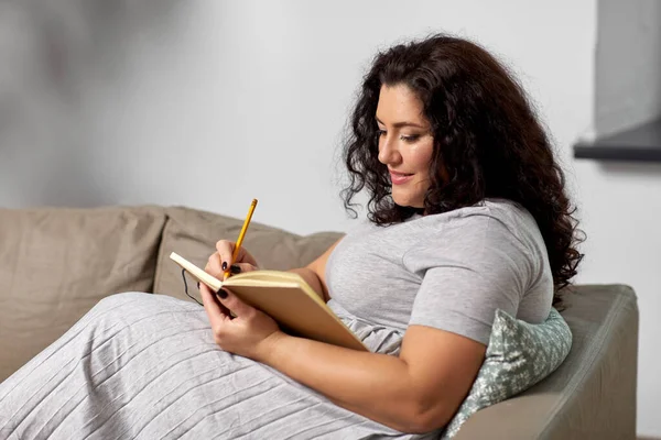 Felice giovane donna con diario sul divano di casa — Foto Stock