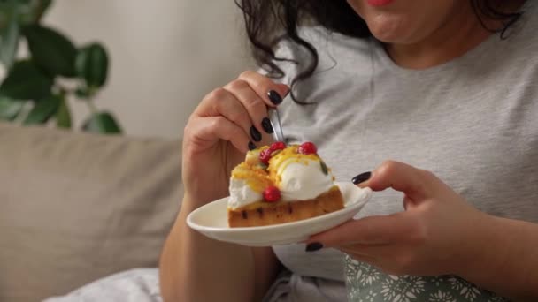 Glimlachende jonge vrouw eten taart thuis — Stockvideo